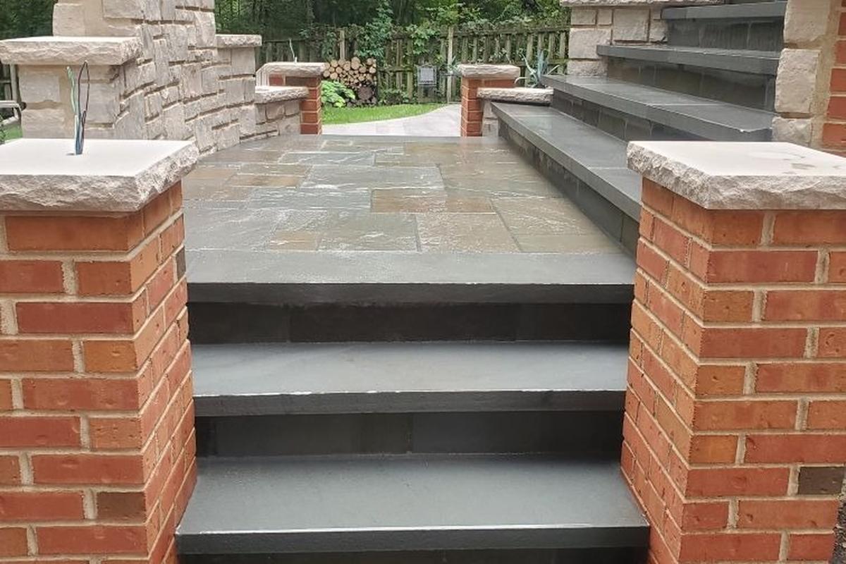 Red brick pillars with limestone caps beside new stone steps, built by WJC Construction
