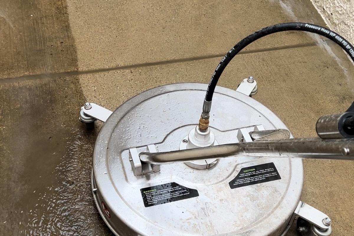 A surface cleaner power washing concrete, half clean and half dirty