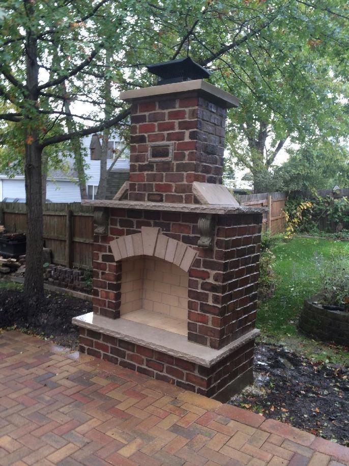 Brick outdoor fireplace. Brick fireplace with a limestone hearth, beside a brick paver patio.