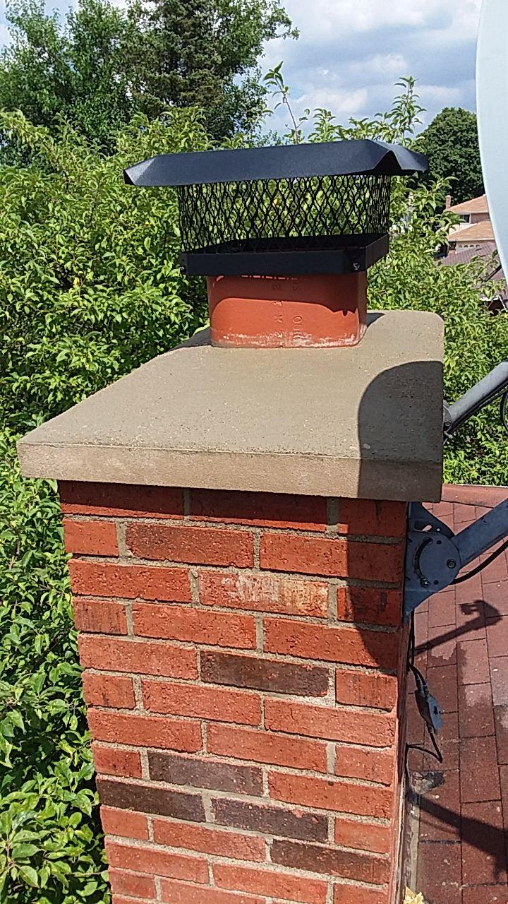 Chimney crown and cap. Brick chimney with a new concrete crown and metal cap.