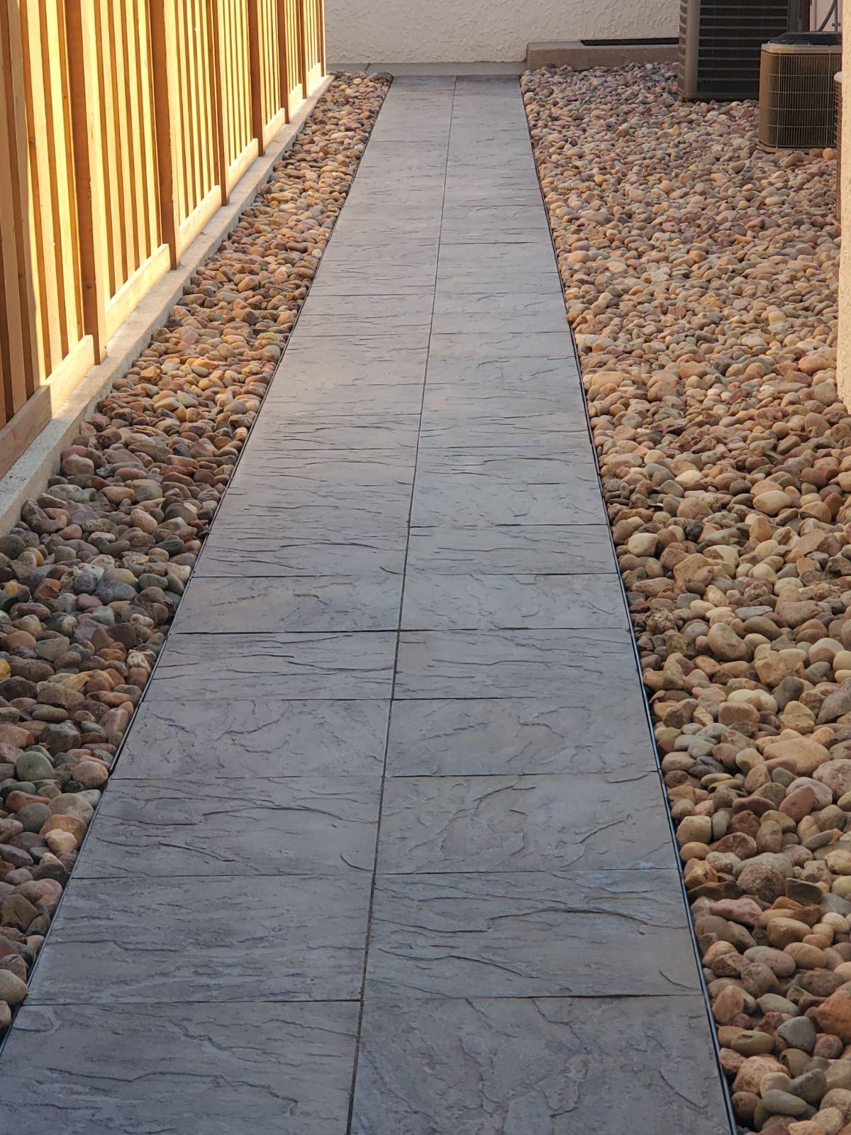 Side walkway. Stone walkway along the side of a house with river rock on both sides.
